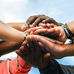 Multiracial teenagers joining hands together in cooperation