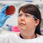 Scientist looking up at a Petri dish